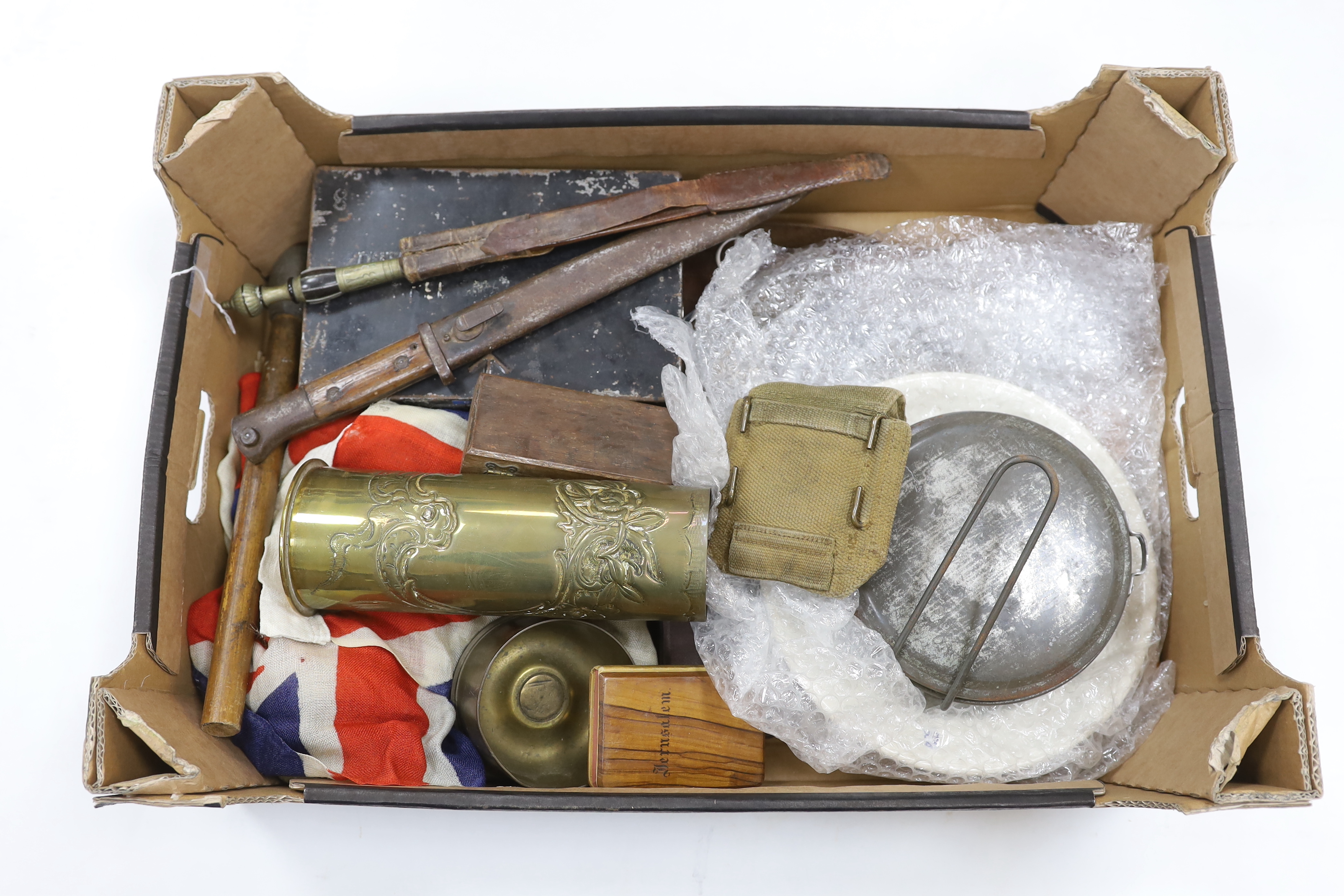 A collection of militaria including; a pith helmet, a T.G. Co. Ltd. Mk.III compass, a cased protractor, a Union flag, a trench art shell casing, a bayonet, an Indian knife, a mess plate with ERII cypher, etc.